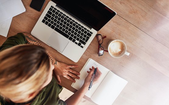 mulher ao computador e a escrever num bloco