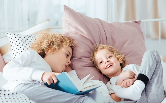 crianças a ler livro na cama
