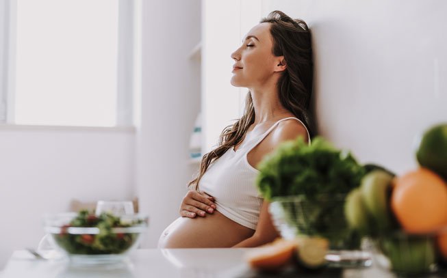 mulher grávida com a mão na barriga